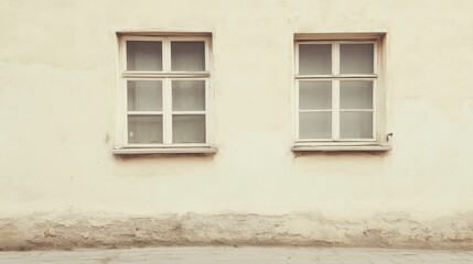 Two vintage windows on a weathered, light beige wall.