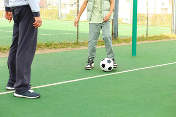 The feet of three individuals are captured mid-action as they play ball on an outdoor sports field.
