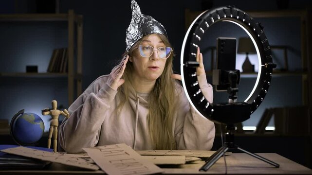 Strange crazy vlogger with cellphone, paranoid woman streaming at home conspiracy theory broadcasting in vlog, telling the theory of fake news and world government. blogging, conspiracy theory