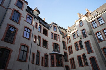 Obraz premium Blick aus dem Hinterhof auf schöne sanierte Fassaden alter Wohnhäuser in Weiß und Naturfarben vor blauem Himmel im Sonnenschein im Stadtteil Mitte in der Hauptstadt Berlin