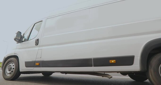White cargo minibus on the highway. A white delivery or service van speeds down the road.