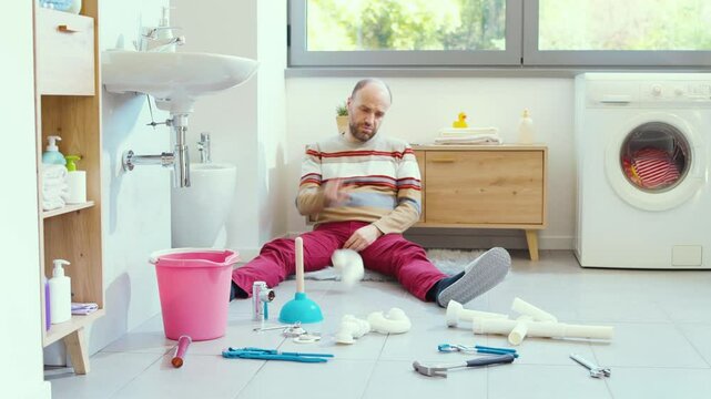 Frustrated man unable to repair the leaky bathroom sink by himself