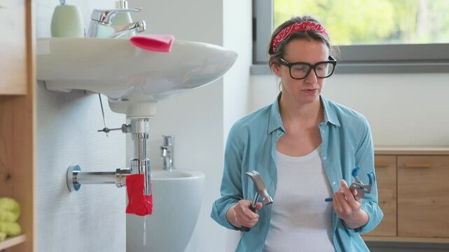 Confused woman trying to repair a leaking pipe by herself
