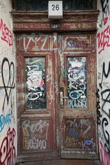 Heruntergekommener Hauseingang mit Haustür und Holztür mit wilden Graffiti eines Altbau am Prenzlauer Berg oder Prenzlberg in der Hauptstadt Berlin