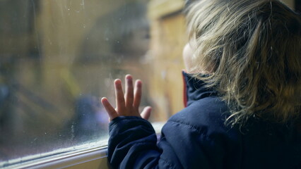 Baby toddler standing by window looking out. Child wanting to go outside