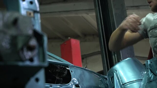 young mechanic repairs and installs an old gray car after a road accident (157)