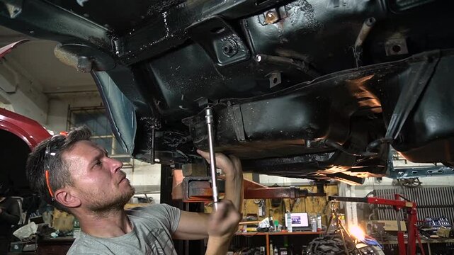 young mechanic repairs and installs an old gray car after a road accident (157)