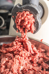 A meat grinder makes minced beef meat. Close-up. High quality photo