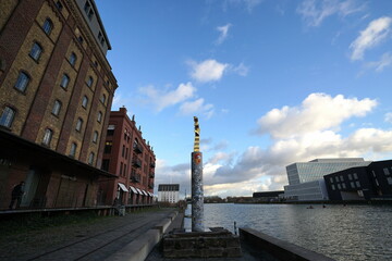 Alter Getreidespeicher und Lagerhaus aus rotbraunem Backstein mit Statue auf einer S&auml;ule vor blauem Himmel mit wei&szlig;en Wolken am Kreativkai am alten Hafen von M&uuml;nster in Westfalen im M&uuml;nsterland