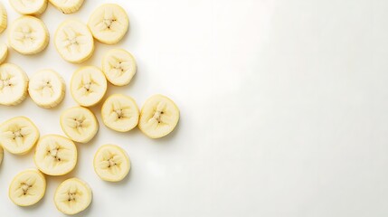 A white background with a group of sliced bananas scattered across it. The bananas are arranged in a somewhat random pattern, with some slices overlapping or close to each other.