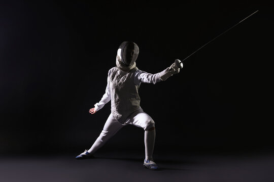 Fencer with epee practicing on dark background