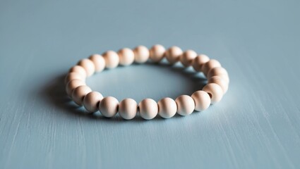 The image features a simple, elegant bracelet made out of round wooden beads, with a smooth finish, laid out on a textured blue surface that provides a serene backdrop highlighting the natural beauty
