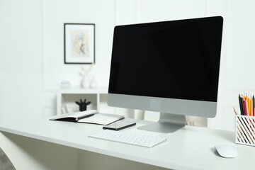 Modern workplace with computer and stationery on white desk indoors