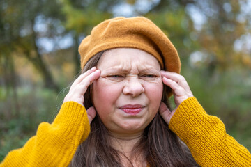 mature woman suffering from severe migraine, holding head in pain, pained expression, migraine...