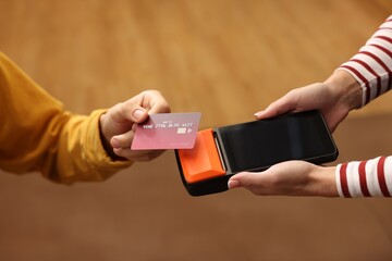 Man paying with credit card via terminal in cafe, closeup