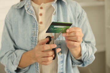 Woman cutting plastic credit card indoors, closeup