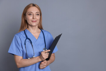 Doctor with stethoscope and clipboard on gray background