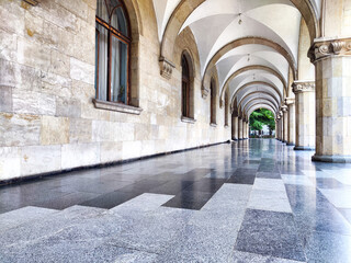 Obraz premium Historic architectural beauty featuring arched corridors and polished stone floors in a quiet urban setting