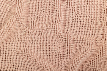 Texture of terry carpet with folds. Beige carpet texture. Beige background with loops.