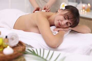 Obraz na płótnie Canvas Young woman receiving hot stone massage in spa salon