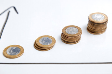 coins on white surface and arrows indicating time and earnings growth