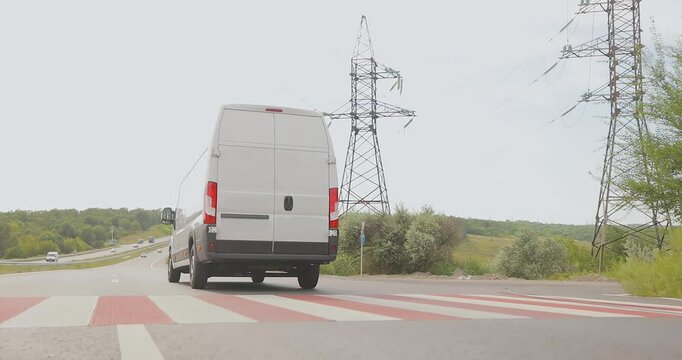White Cargo minibus driving along the highway. A white delivery or service van speeds down the road.