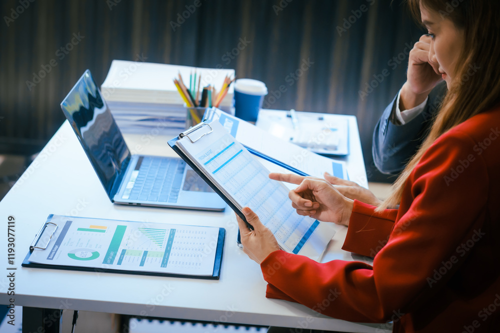 Wall mural A businessman and woman sit at a modern office table, smiling and discussing a new project or business startup. They collaborate with a laptop, focusing on strategic planning and teamwork