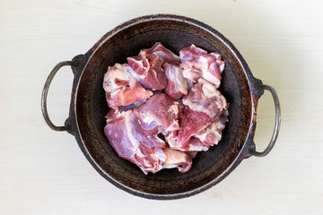 Fresh, raw mutton or goat meat in a karahi, ready for cooking. Top view.