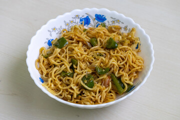 A bowl of flavorful homemade noodles, stir-fried with vibrant green bell pepper, juicy tomatoes, and spicy chili peppers, served in a white bowl.