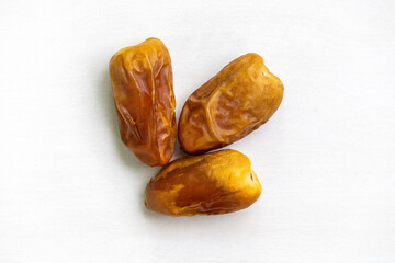 Three dried date palm fruits isolated against a white background. Top view.
