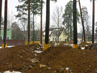 construction is underway on the site, there is a pile of clay and the trees are covered with boards
