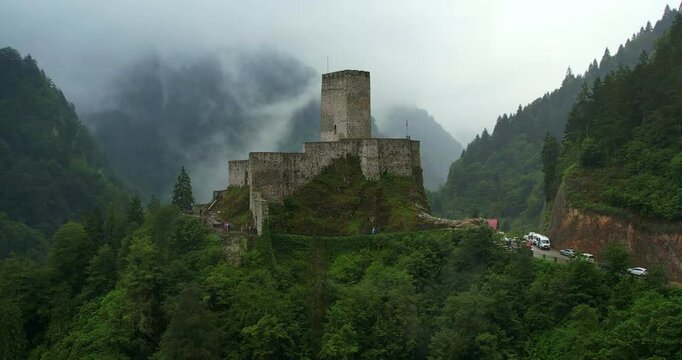 4K aerial video capturing a medieval castle enveloped by a foggy forest, highlighting the mysterious ambiance and ancient architecture amidst the dense woodland. Rize, Turkey