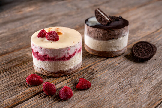 Mini raspberry and chocolate cheesecakes with cookie base on a rustic wooden table