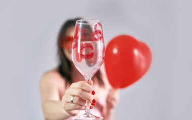 A girl holds a glass of champagne in her hands, celebrating Valentine's Day with joy and love.