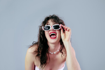 Woman holding her glasses frame and smiling widely, ready for a Valentine's Day party celebration.