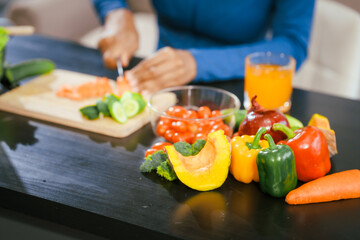 African American woman sitting  table, enjoying a colorful salad orange juice, highlighting the health benefits of five-color fruits vegetables, rich in antioxidants, reducing cancer risks,wellness