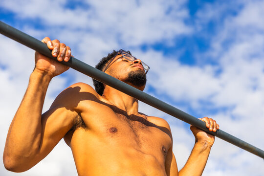 A man is doing pull-ups outdoors, fit person training