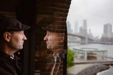 Thinking man looking out the window with Brooklyn Bridge in the background, New York City, USA