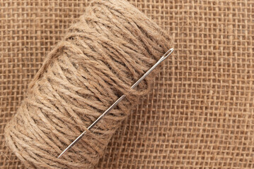 Jute rope with a needle lies on burlap. Handmade