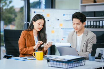 Young businessman and woman are working together at a table, discussing a proposal for cooperation. They review documents focused on business marketing strategies, finance, effective collaboration