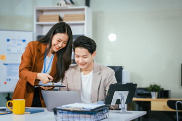 Young businessman and woman are working together at a table, discussing a proposal for cooperation. They review documents focused on business marketing strategies, finance, effective collaboration