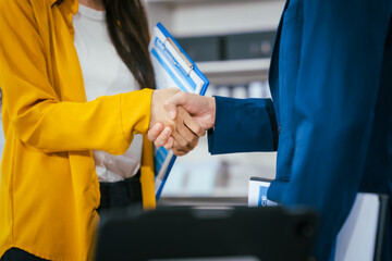A businessman and businesswoman shake hands during a meeting at the office,signifying...
