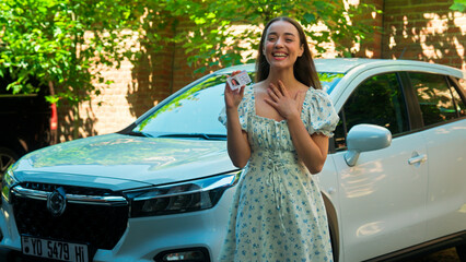Happy excited amazed Caucasian woman female girl student client buyer buy new car automobile showing driver license successfully passed exam test driving lessons celebrating excitement at city street