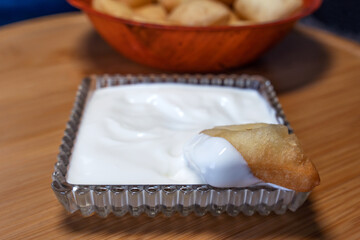 A close-up of a crystal bowl with sour cream (kaymak) and soaked in it boorsok (baursak), a national traditional dish of the peoples of Central Asia.