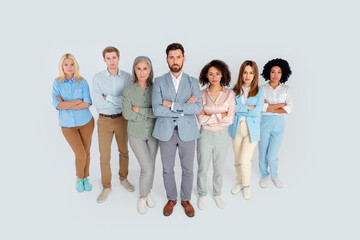 Fototapeta premium Diverse group of business professionals standing confidently on a grey background, symbolizing teamwork and collaboration
