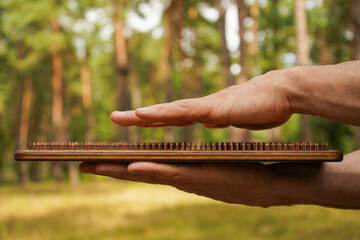 Awareness and rethinking over slight pain. A man holds a Sadhu board made of wood and nails in his hand. The hand barely touches the nails, a close-up image.