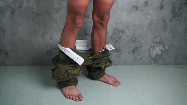 a man takes off his cargo pants and lets them fall to the floor. a male with brown skin tone with his trouser pants down and sagging