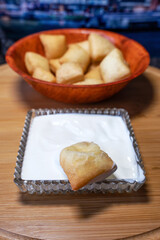Close-up of a crystal bowl with sour cream (kaymak) and soaked in it boorsok (baursak), a national traditional dish of the peoples of Central Asia, vertical photo.