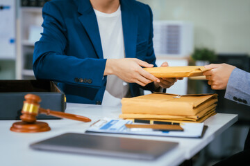 A female lawyer at a law firm is delivering documents and discussing business matters with a male...