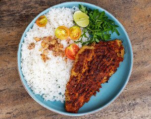 Ikan bakar parape. A traditional Indonesian food menu of grilled fish cooked with a sprinkling of hot chili seasoning, eaten with a portion of white rice. Top view. Flat lay photo.